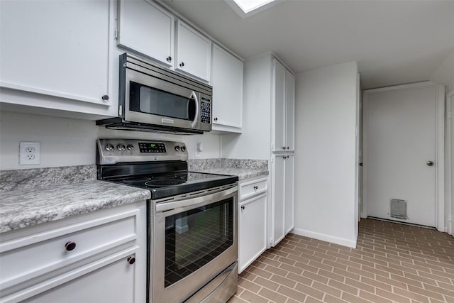 7450 Holly Hill Dr Unit 115, Dallas, TX 75231 - kitchen featuring stainless steel appliances, light countertops, brick patterned flooring, and white cabinetry