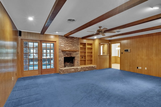 824 Captain Shreve Dr, Shreveport, LA 71105 - unfurnished living room with wooden walls, carpet floors, beam ceiling, ceiling fan, and french doors