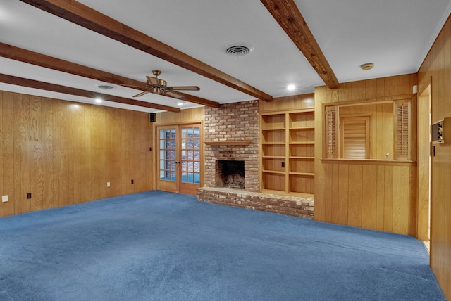 824 Captain Shreve Dr, Shreveport, LA 71105 - unfurnished living room with wood walls, carpet floors, ceiling fan, beamed ceiling, and a brick fireplace