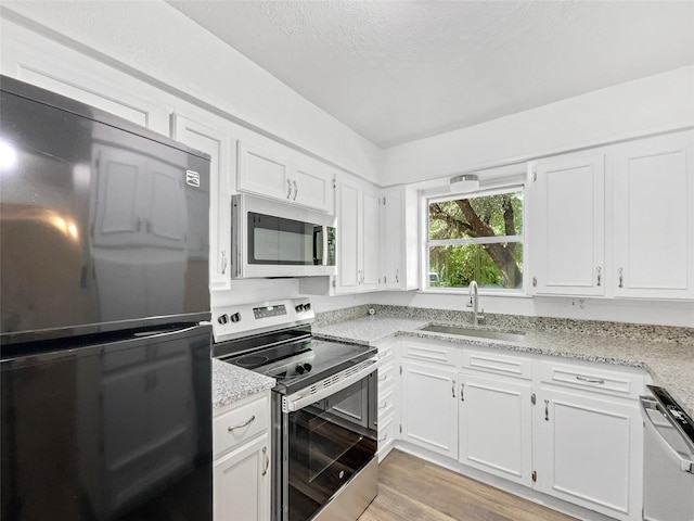 5941 Ten Mile Bridge Rd, Fort Worth, TX 76135 - kitchen featuring appliances with stainless steel finishes, light stone counters, and white cabinetry