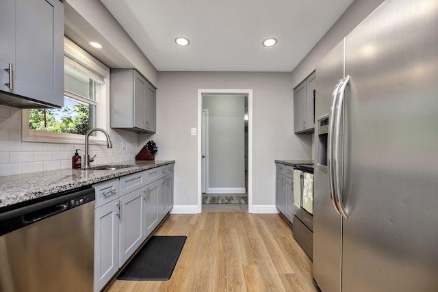 5125 Susan Lee Ln, North Richland Hills, TX 76180 - kitchen featuring appliances with stainless steel finishes, light wood-style flooring, tasteful backsplash, recessed lighting, and light stone counters