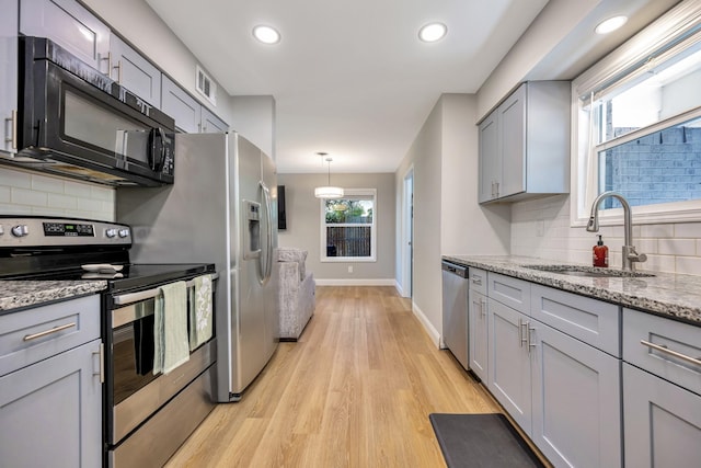 5125 Susan Lee Ln, North Richland Hills, TX 76180 - kitchen with appliances with stainless steel finishes, gray cabinets, decorative backsplash, light wood-style floors, and light stone counters