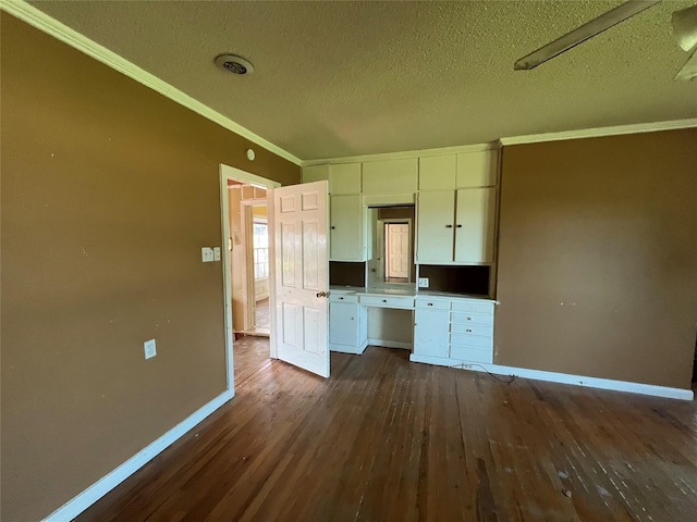 2928 Pine Ave, Waco, TX 76708 - kitchen featuring dark wood finished floors, crown molding, white cabinets, a textured ceiling, and built in desk
