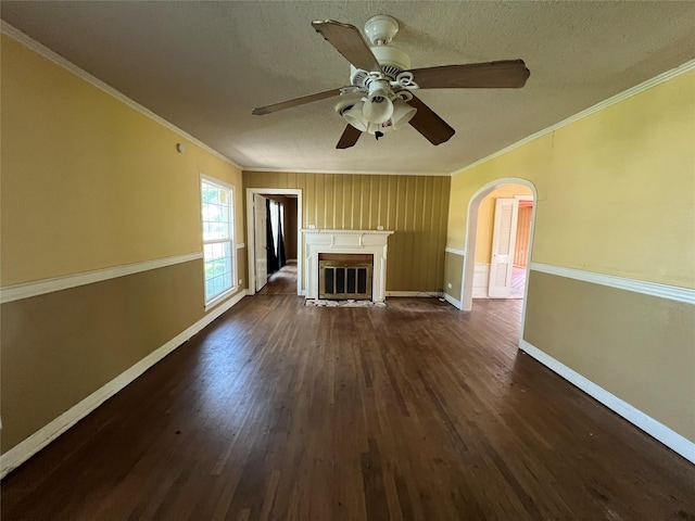 2928 Pine Ave, Waco, TX 76708 - unfurnished living room with dark wood-type flooring, crown molding, arched walkways, a ceiling fan, and a glass covered fireplace