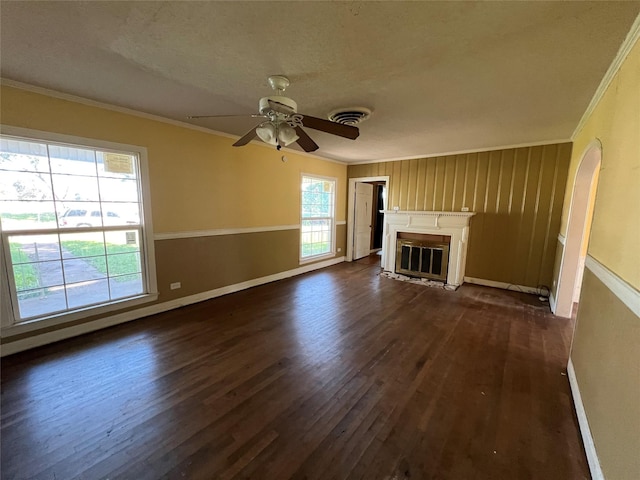 2928 Pine Ave, Waco, TX 76708 - unfurnished living room featuring ornamental molding, dark wood-style flooring, a glass covered fireplace, a ceiling fan, and arched walkways