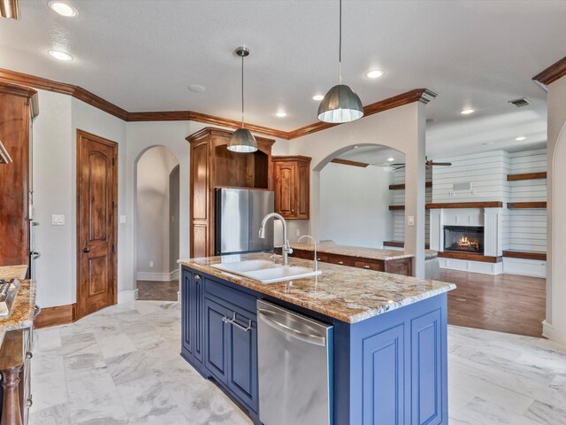 830 Cemetery Rd, Decatur, TX 76234 - kitchen featuring stainless steel appliances, arched walkways, blue cabinetry, crown molding, and a lit fireplace