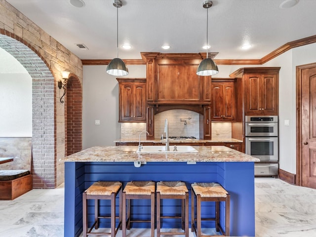 830 Cemetery Rd, Decatur, TX 76234 - kitchen featuring light stone counters, tasteful backsplash, stainless steel double oven, an island with sink, and a kitchen bar