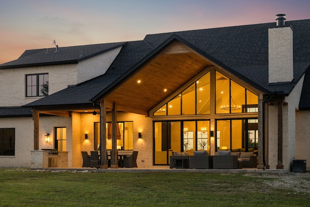 1890 Mcconnell Rd, Gunter, TX 75058 - back of house at dusk featuring an outdoor hangout area, a chimney, an outdoor kitchen, a yard, and a patio area
