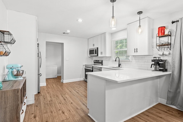 1204 Maxfield St, Bellmead, TX 76705 - kitchen with stainless steel appliances, white cabinets, a peninsula, light wood-style flooring, and backsplash
