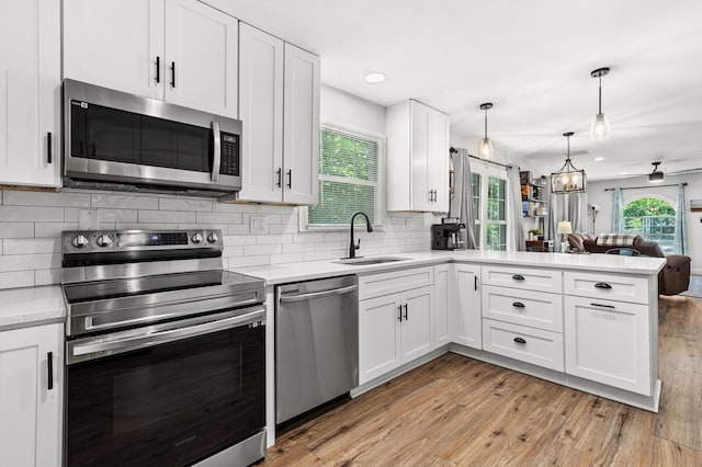 1204 Maxfield St, Bellmead, TX 76705 - kitchen featuring appliances with stainless steel finishes, a peninsula, light countertops, white cabinets, and recessed lighting