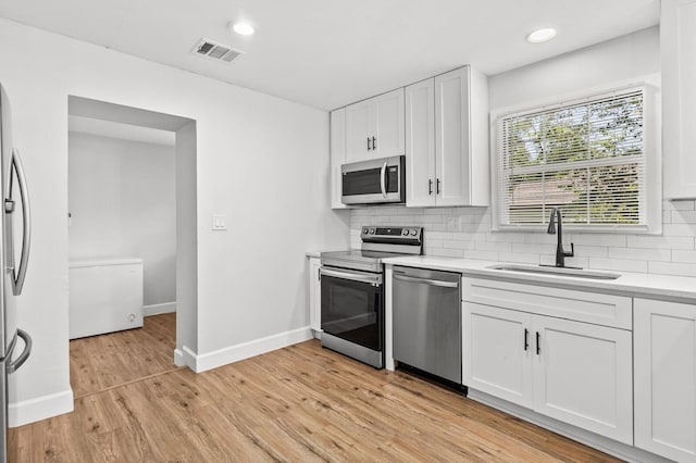 1204 Maxfield St, Bellmead, TX 76705 - kitchen featuring appliances with stainless steel finishes, white cabinets, light countertops, decorative backsplash, and light wood-style floors