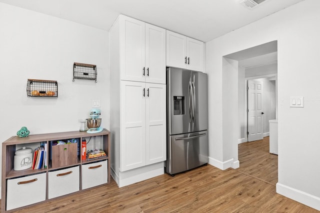 1204 Maxfield St, Bellmead, TX 76705 - kitchen with stainless steel fridge, light wood-style floors, and white cabinetry