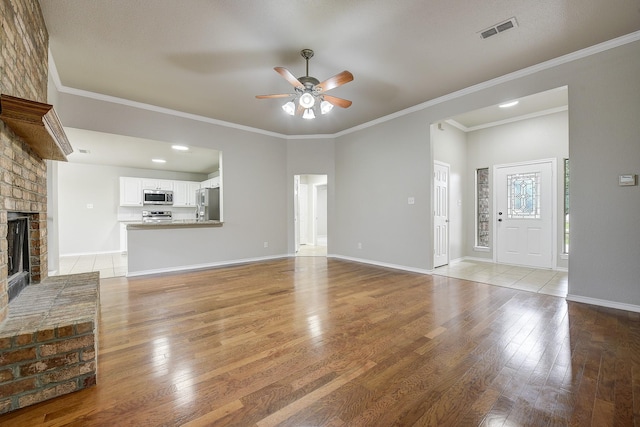 11440 Mitchell Cir, Ponder, TX 76259 - unfurnished living room featuring a ceiling fan, light wood finished floors, a brick fireplace, and crown molding