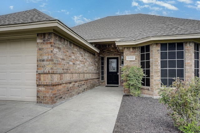 11440 Mitchell Cir, Ponder, TX 76259 - view of exterior entry with roof with shingles, an attached garage, and brick siding