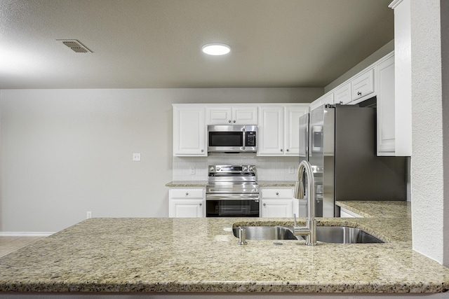 11440 Mitchell Cir, Ponder, TX 76259 - kitchen with appliances with stainless steel finishes, light stone countertops, white cabinetry, backsplash, and a peninsula