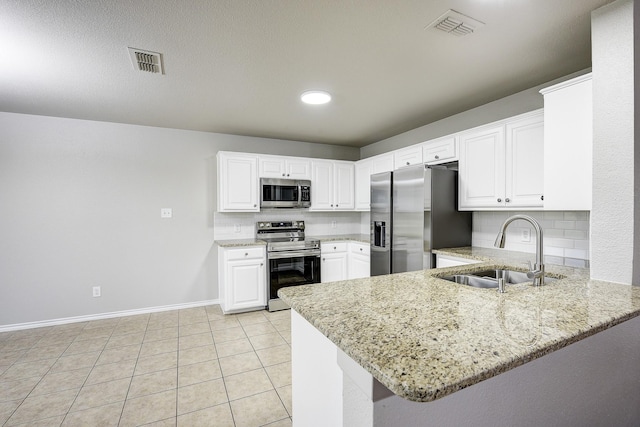 11440 Mitchell Cir, Ponder, TX 76259 - kitchen featuring appliances with stainless steel finishes, a peninsula, light stone countertops, and recessed lighting