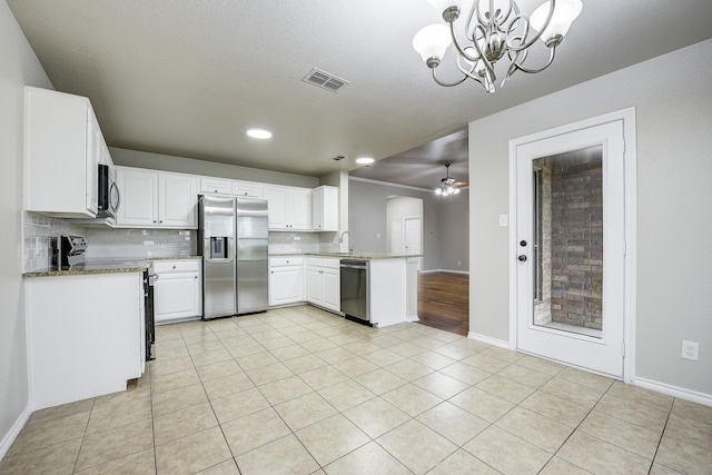 11440 Mitchell Cir, Ponder, TX 76259 - kitchen with appliances with stainless steel finishes, a chandelier, light tile patterned flooring, light stone counters, and white cabinetry