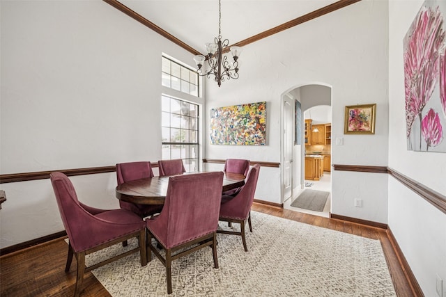 5210 Masters Ct, Midlothian, TX 76065 - dining area featuring wood finished floors, a chandelier, arched walkways, crown molding, and a towering ceiling