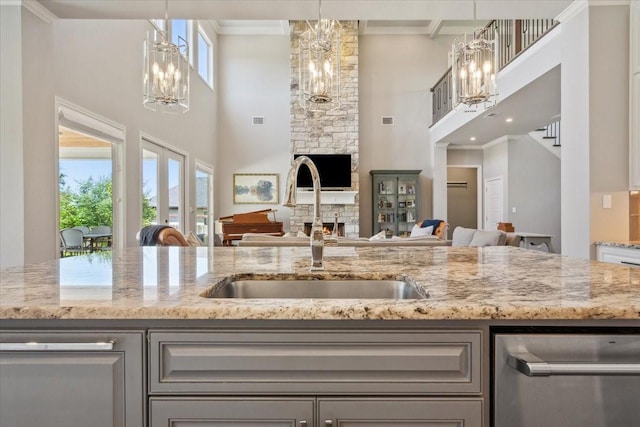400 Wycliff Dr, China Spring, TX 76633 - kitchen with a chandelier, a towering ceiling, stainless steel dishwasher, a stone fireplace, and light stone counters
