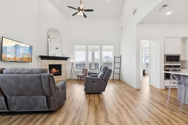 1814 Cypress Gap Trl, Mansfield, TX 76063 - living area featuring a ceiling fan, arched walkways, high vaulted ceiling, a stone fireplace, and light wood-style flooring