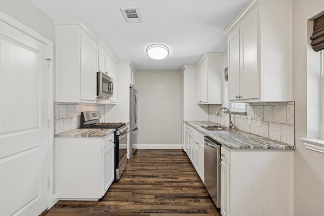 4632 Ivanhoe Dr, Fort Worth, TX 76132 - kitchen with appliances with stainless steel finishes, dark wood-type flooring, decorative backsplash, white cabinets, and light stone countertops