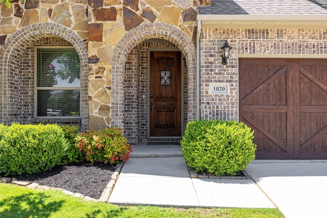 1020 Perennial Ln, Little Elm, TX 75068 - entrance to property with brick siding, a garage, stone siding, and roof with shingles