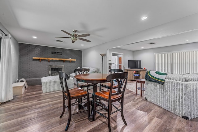 1007 College Ave, Glen Rose, TX 76043 - dining room with a fireplace, wood finished floors, a ceiling fan, brick wall, and recessed lighting