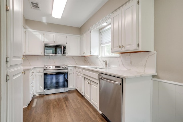 555 Meadowbrook Dr, Burleson, TX 76028 - kitchen featuring appliances with stainless steel finishes, a wainscoted wall, white cabinets, and decorative backsplash