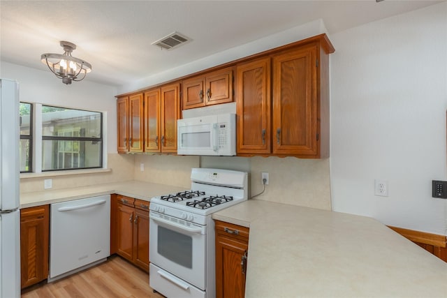 4525 Midway Rd, Weatherford, TX 76085 - kitchen with white appliances, brown cabinetry, light countertops, light wood finished floors, and a chandelier