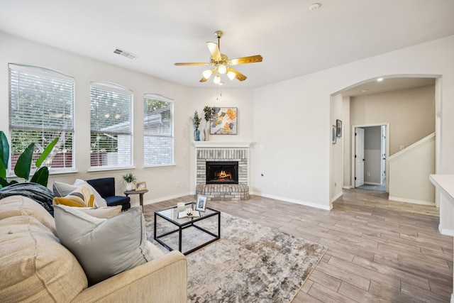 3341 Woodglen Dr, Mckinney, TX 75071 - living area with a ceiling fan, arched walkways, a brick fireplace, and light wood-type flooring
