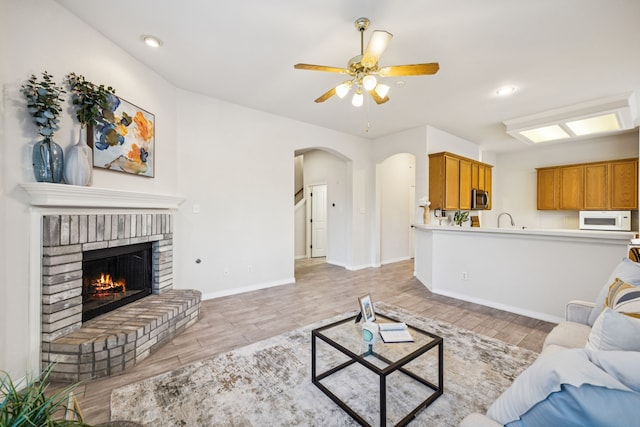 3341 Woodglen Dr, Mckinney, TX 75071 - living room with light wood-style flooring, arched walkways, a brick fireplace, ceiling fan, and recessed lighting