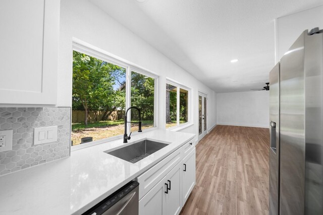 1214 Cove Dr, Garland, TX 75040 - kitchen with appliances with stainless steel finishes, light countertops, decorative backsplash, white cabinetry, and light wood-style flooring