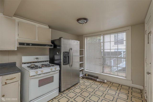 538 Dalzell St, Shreveport, LA 71104 - kitchen with gas range gas stove, under cabinet range hood, stainless steel refrigerator with ice dispenser, light floors, and dark countertops