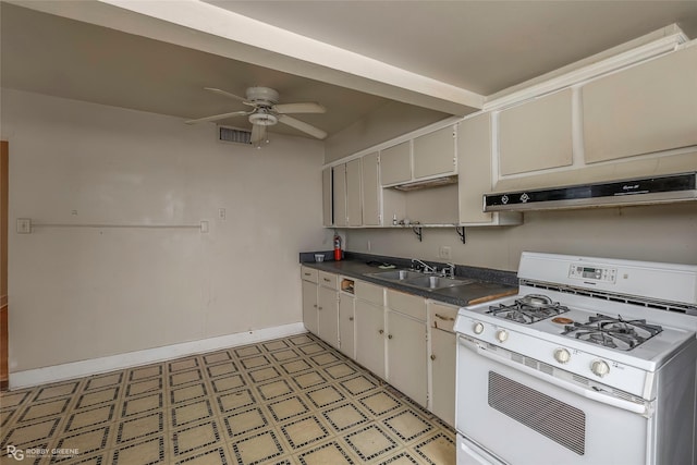 538 Dalzell St, Shreveport, LA 71104 - kitchen with white gas range, under cabinet range hood, light flooring, dark countertops, and a ceiling fan