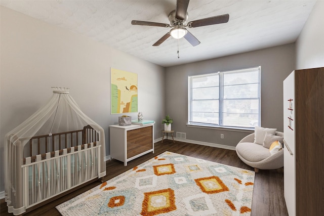 3209 Pecan Ln, Garland, TX 75041 - bedroom with a nursery area, dark wood-style flooring, and a ceiling fan