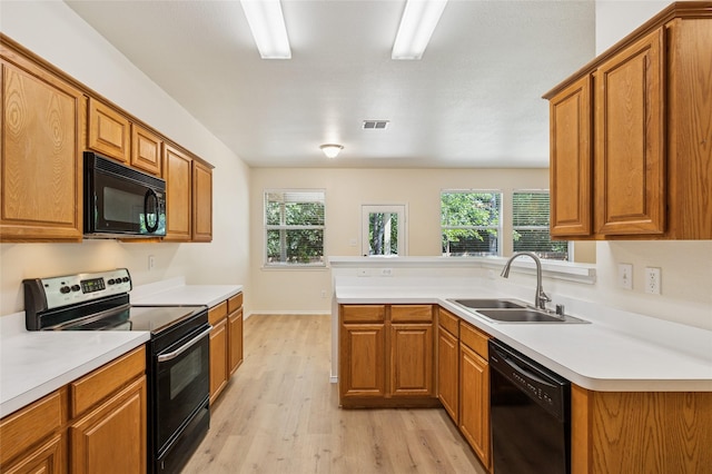 2409 Spruce Ct, Little Elm, TX 75068 - kitchen featuring black appliances, light wood finished floors, brown cabinetry, a peninsula, and light countertops