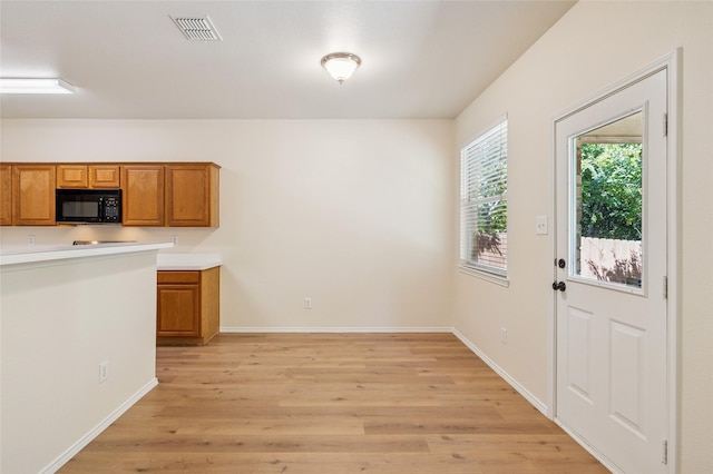 2409 Spruce Ct, Little Elm, TX 75068 - kitchen featuring black microwave, brown cabinets, light wood-style flooring, and light countertops