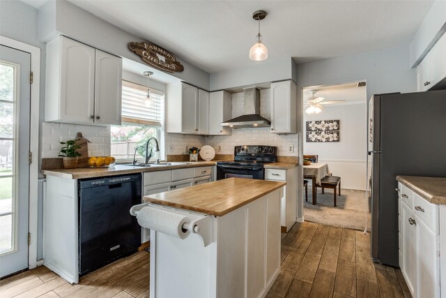 1105 Pyramid Dr, Garland, TX 75040 - kitchen featuring wall chimney exhaust hood, black appliances, wood counters, and wood finished floors