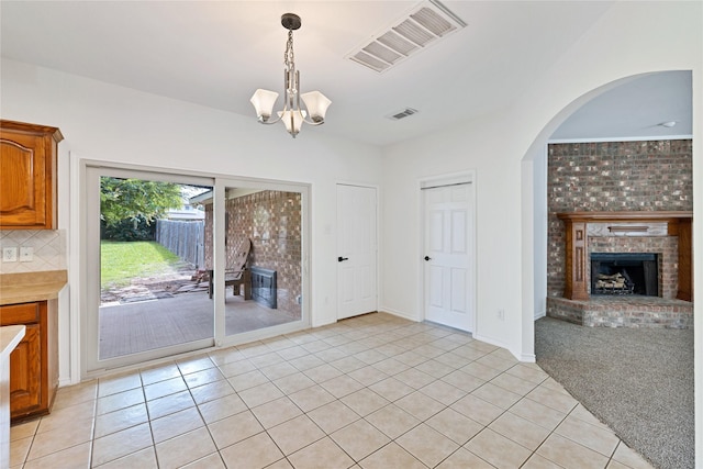 1645 Ashbourne Dr, Rockwall, TX 75087 - unfurnished dining area with a fireplace, a chandelier, light tile patterned floors, and arched walkways