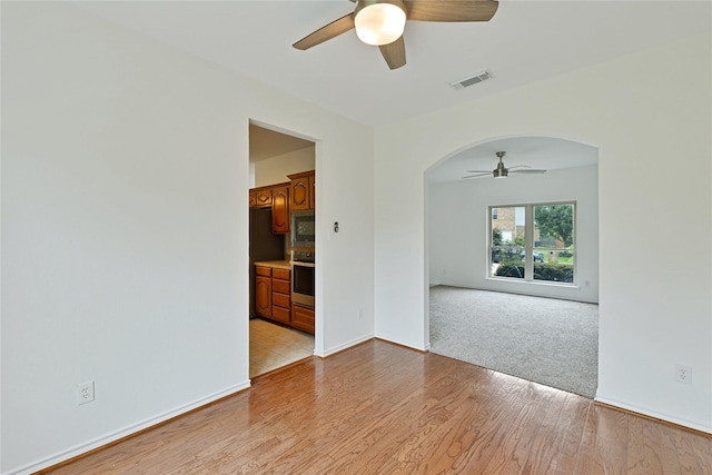 1645 Ashbourne Dr, Rockwall, TX 75087 - empty room featuring a ceiling fan, arched walkways, and light wood finished floors