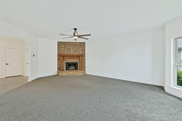 1645 Ashbourne Dr, Rockwall, TX 75087 - unfurnished living room with carpet floors, ceiling fan, arched walkways, a brick fireplace, and tile patterned flooring