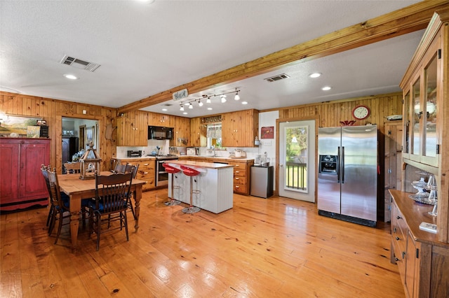1243 Vz County Road 1903, Fruitvale, TX 75127 - kitchen with stainless steel appliances, wooden walls, a center island, light wood finished floors, and beam ceiling