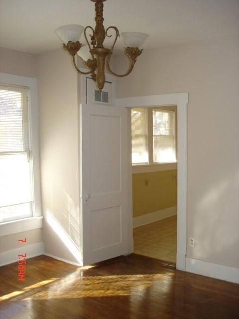 111 N Winnetka Ave, Dallas, TX 75208 - unfurnished room featuring a chandelier, plenty of natural light, and wood finished floors