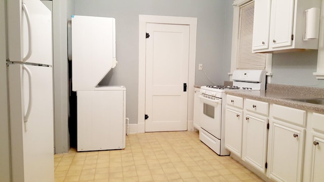 111 N Winnetka Ave, Dallas, TX 75208 - kitchen featuring white appliances, estacked washer and dryer, white cabinetry, and light floors