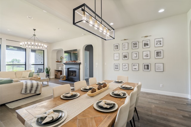 1253 Gray Fox Ln, Frisco, TX 75033 - dining space featuring arched walkways, dark wood-type flooring, recessed lighting, a chandelier, and a fireplace with raised hearth