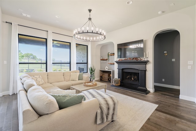 1253 Gray Fox Ln, Frisco, TX 75033 - living area with arched walkways, dark wood-style flooring, a fireplace with raised hearth, a chandelier, and recessed lighting