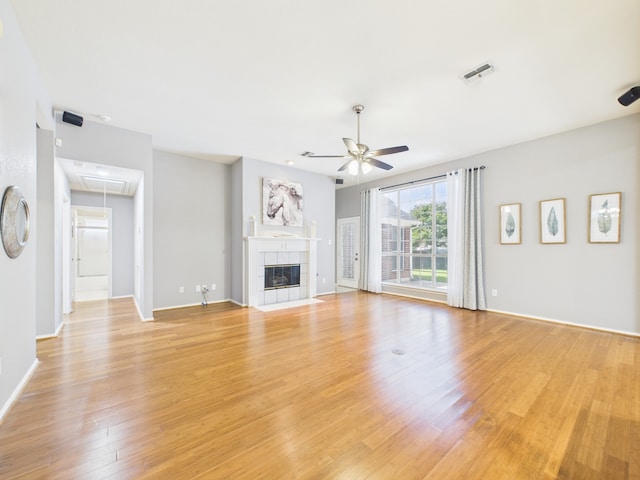 1197 Pleasant Oaks Dr, Lewisville, TX 75067 - unfurnished living room with attic access, a ceiling fan, light wood-type flooring, and a tile fireplace