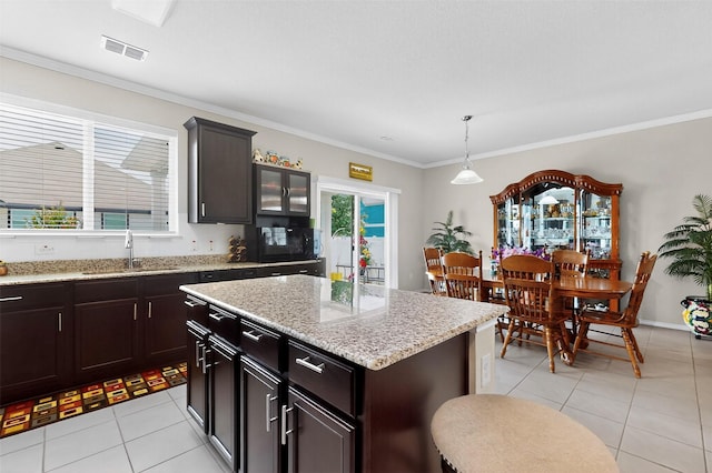 1712 Intervale Rd, Providence Village, TX 76227 - kitchen with light tile patterned floors, black microwave, crown molding, decorative light fixtures, and a kitchen island