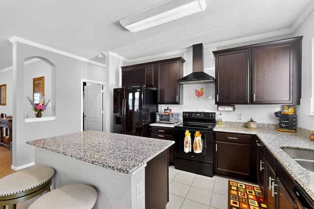 1712 Intervale Rd, Providence Village, TX 76227 - kitchen featuring wall chimney range hood, black appliances, light tile patterned floors, a breakfast bar area, and crown molding