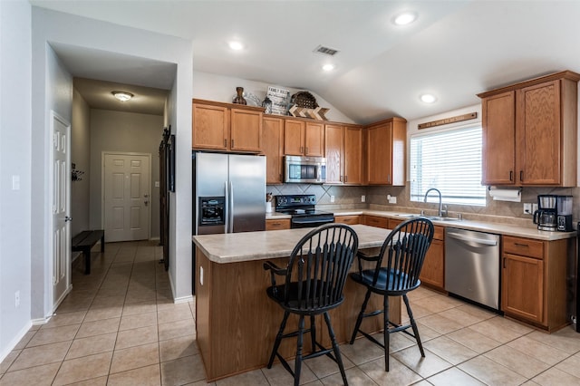 109 Niagara Falls Dr, Anna, TX 75409 - kitchen with appliances with stainless steel finishes, vaulted ceiling, backsplash, brown cabinets, and a kitchen breakfast bar